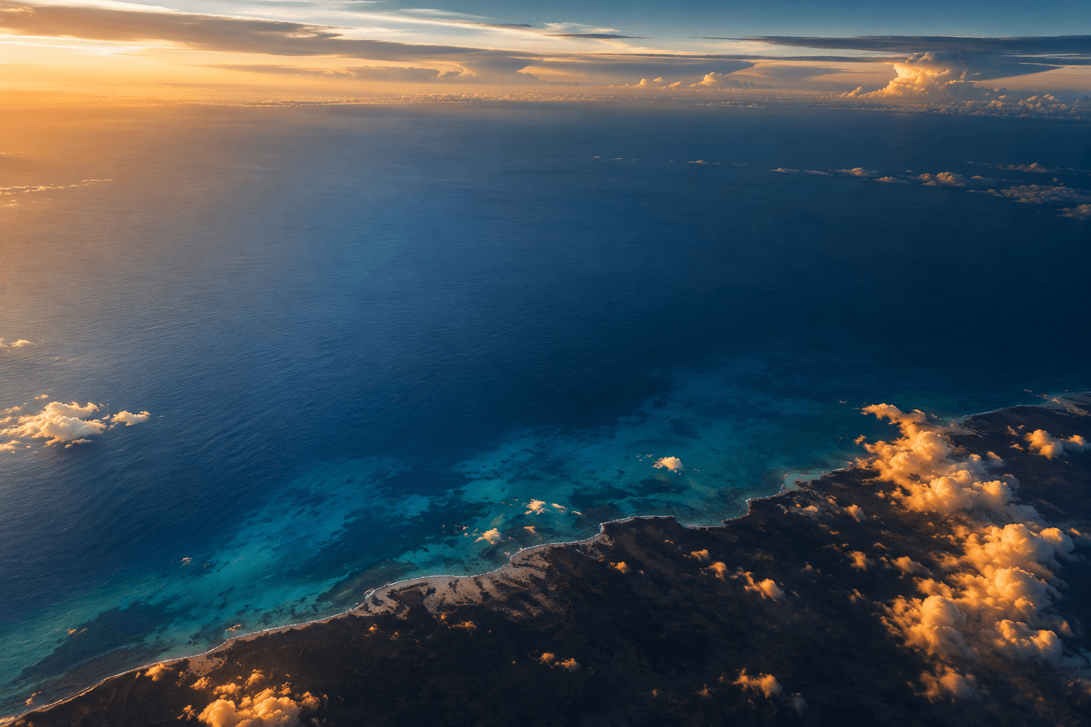 Una fotografía aérea del mar Caribe al amanecer, con el agua que pasa del azul larimar al azul marino profundo.