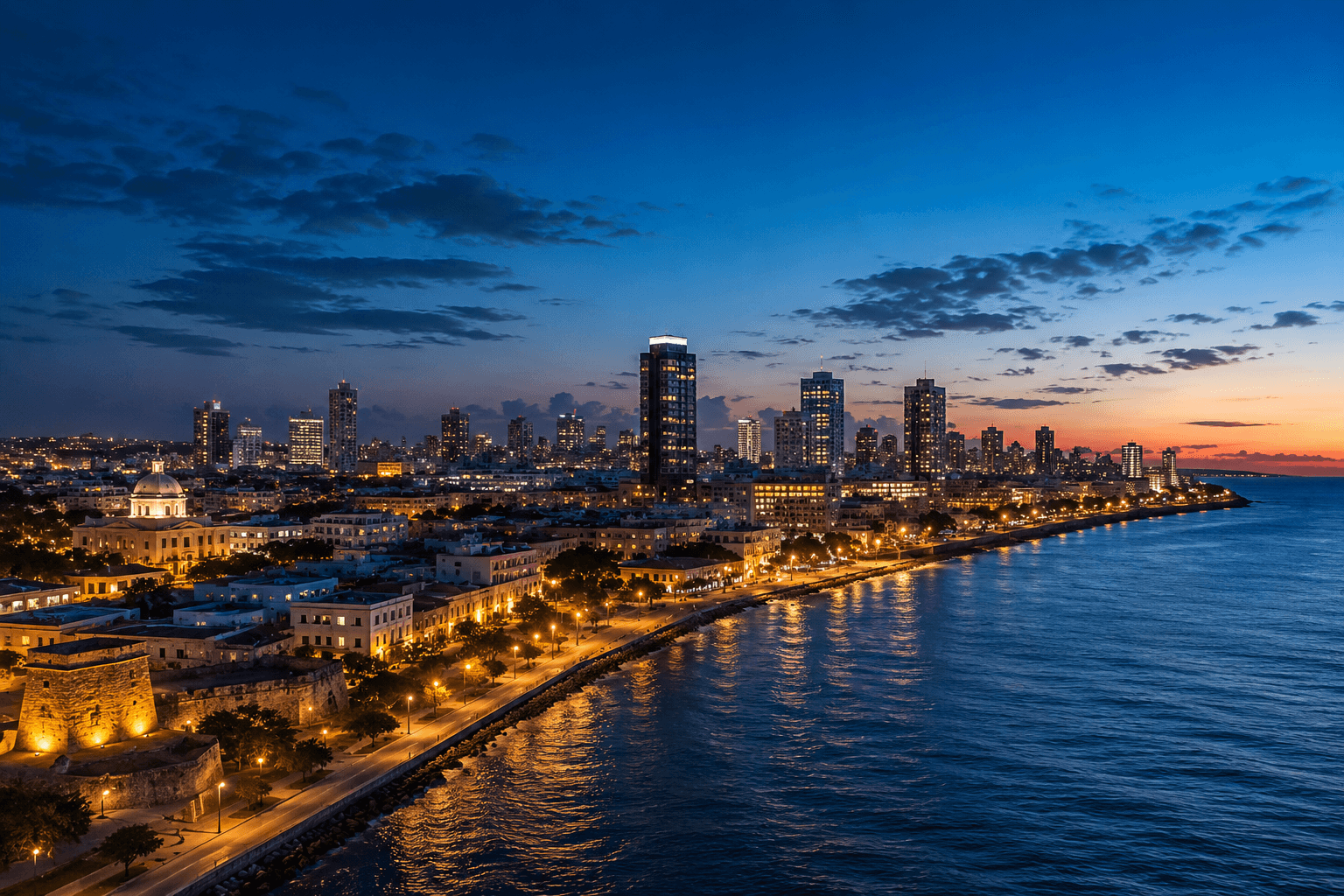 The Santo Domingo skyline at blue hour, with modern commercial towers and the colonial district beside the Caribbean Sea.